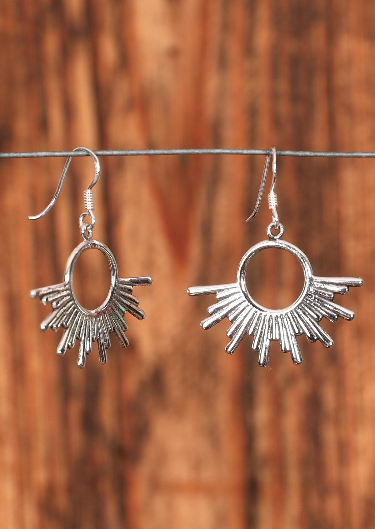 92.5% silver sunshine earrings placed on a wire for display.