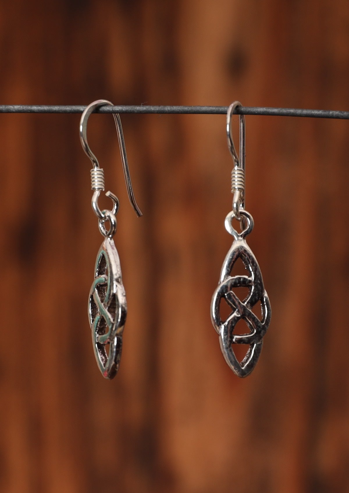 92.5% silver woven Celtic style earrings sitting on a wire for display.