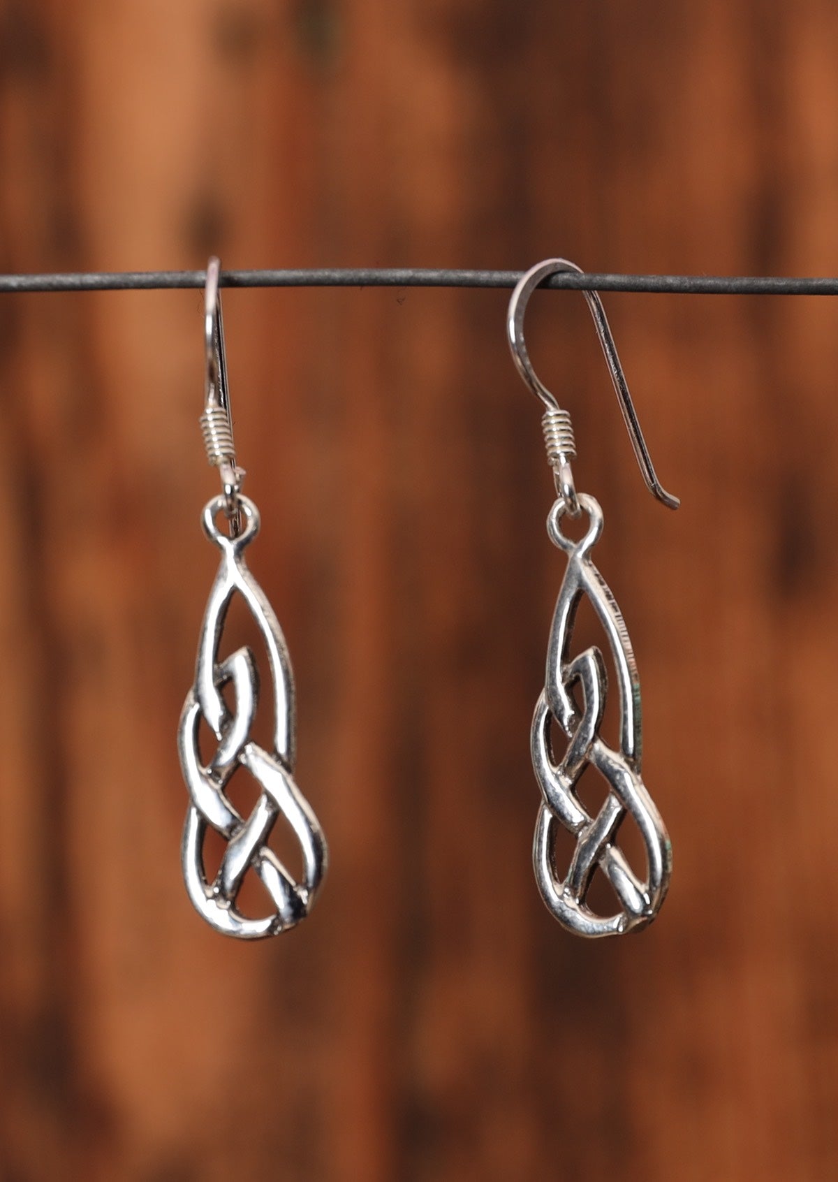92.5% silver woven Celtic droplet earrings sitting on a wire for display.