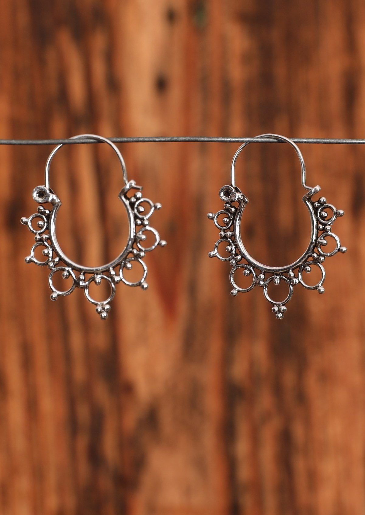 92.5% silver boho style earrings with decorative circles sit on a wire for display.