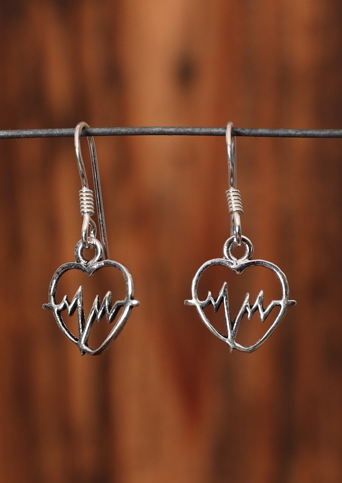 92.5% silver heartbeat earrings on a wire for display.