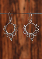 92.5% silver ornate circular boho earrings hanging on a wire for display.