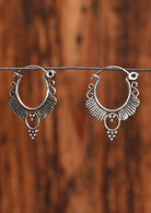 92.5% silver circular ornate earrings hanging on a wire for display.