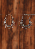 92.5% silver boho heart earrings sit on a wire for display.