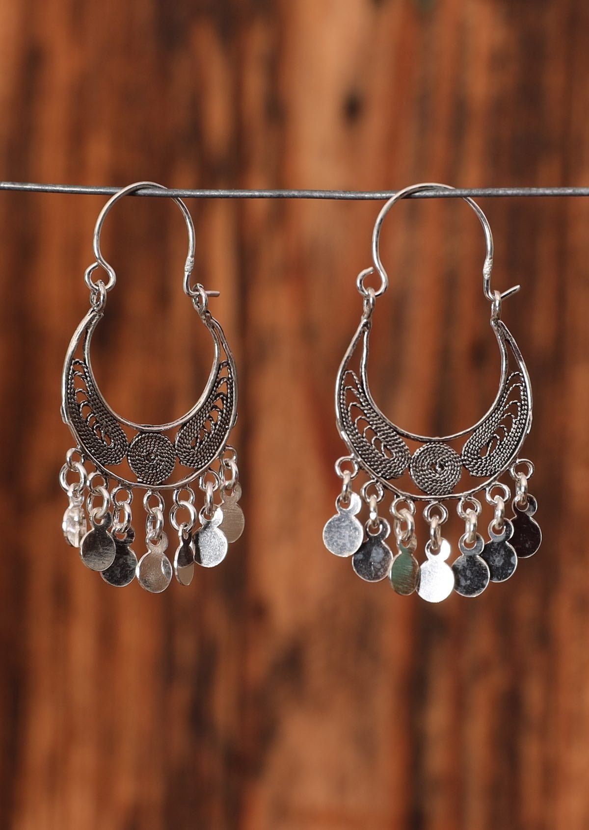92.5% silver gypsy style earrings with dangling circular components sitting on a wire for display.