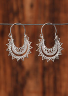 92.5% silver layered lace earrings sit on a wire for display.
