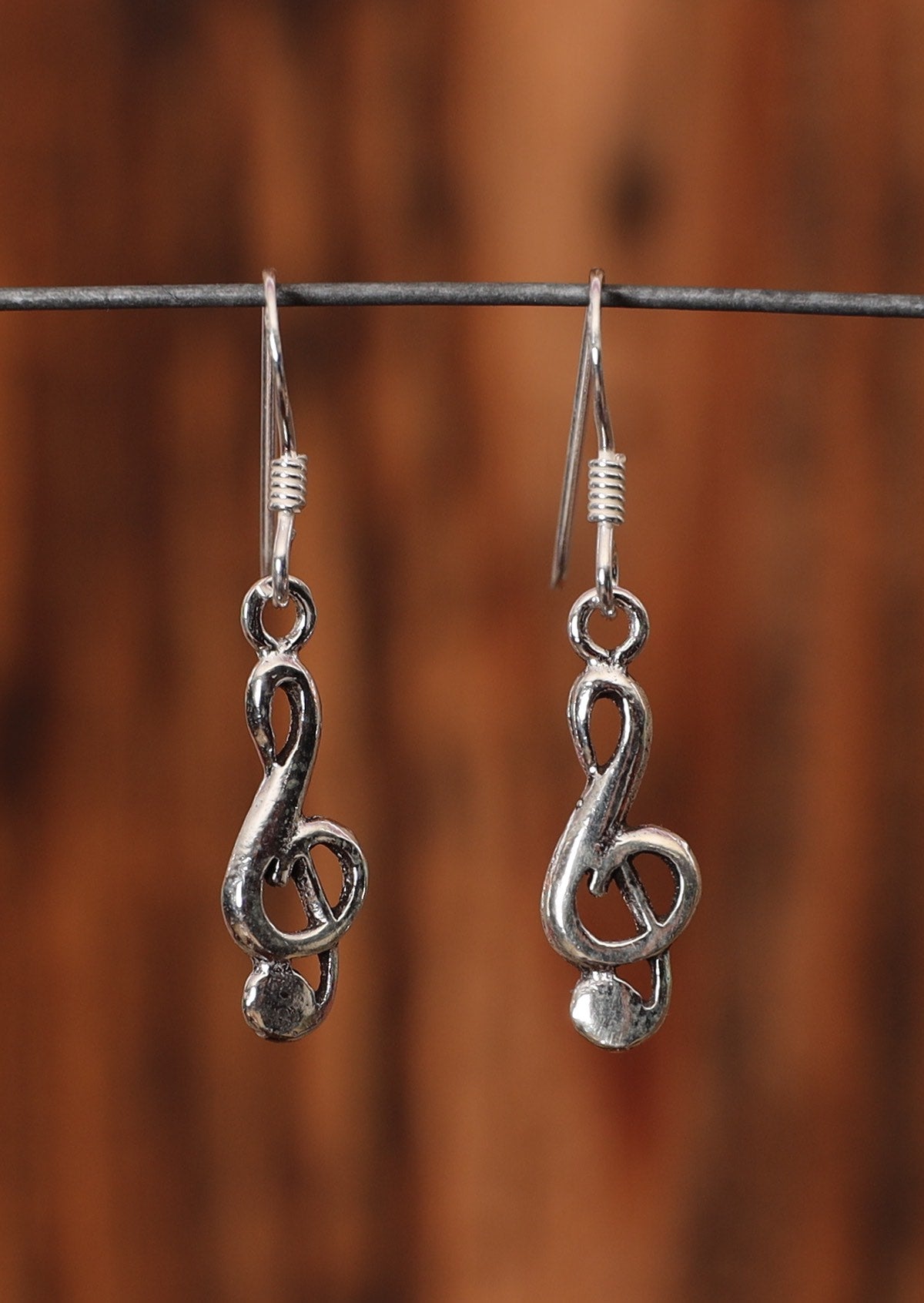 9.25% silver treble clef earrings on a wire for display. 