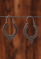 92.5% silver curved earrings sitting on a wire for display.