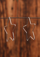 92.5% silver star shaped hoop earrings on a wire for display.