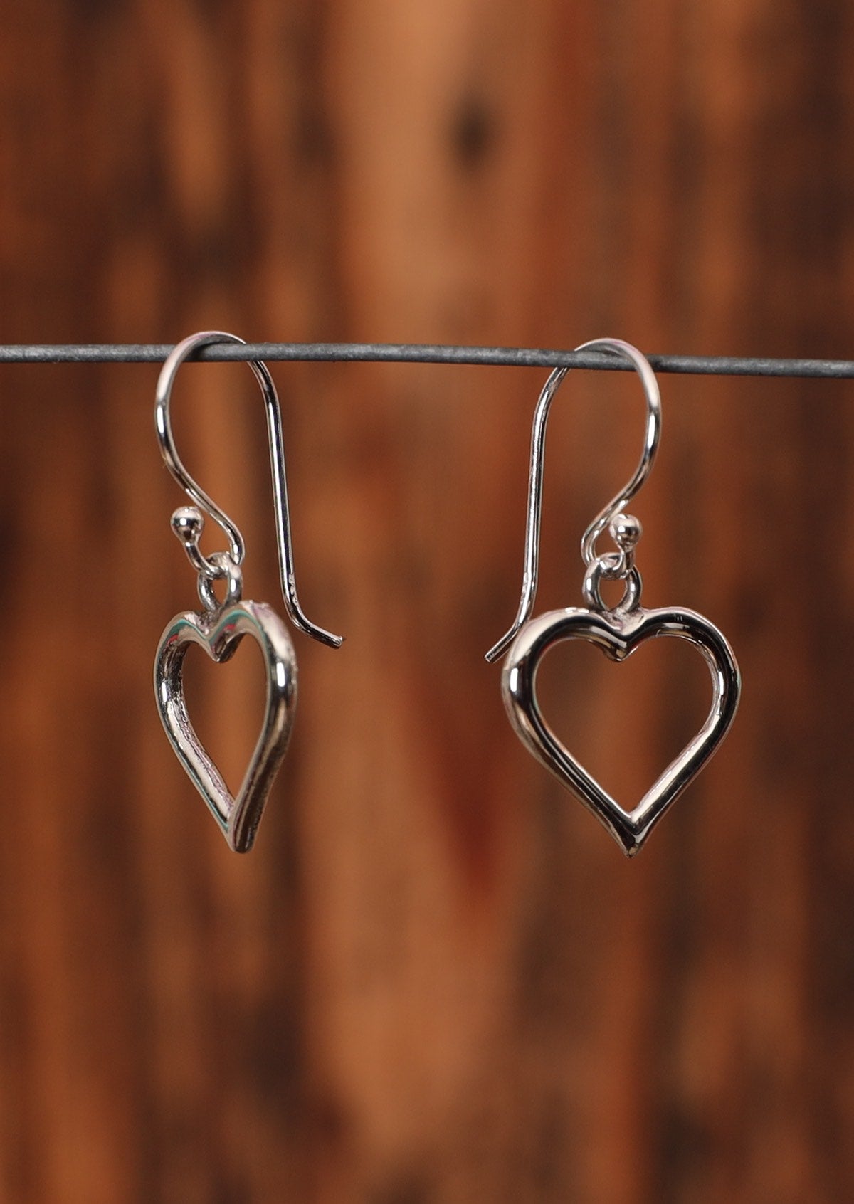 92.5% Silver heart shaped earrings on a wire for display.