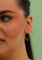 square shaped silver hoop earring on woman's ear