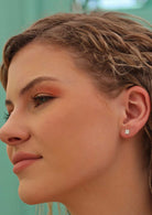 woman with blond hair wearing square silver stud earrings