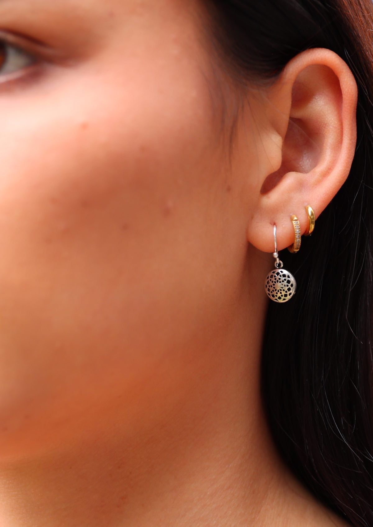 Model wears sterling silver hook earring with 10mm web-like mandala disc