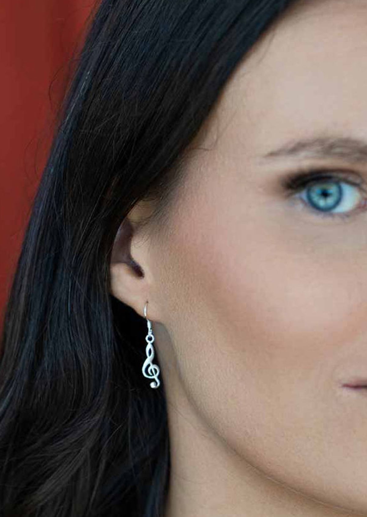 silver music earrings on woman with dark hair
