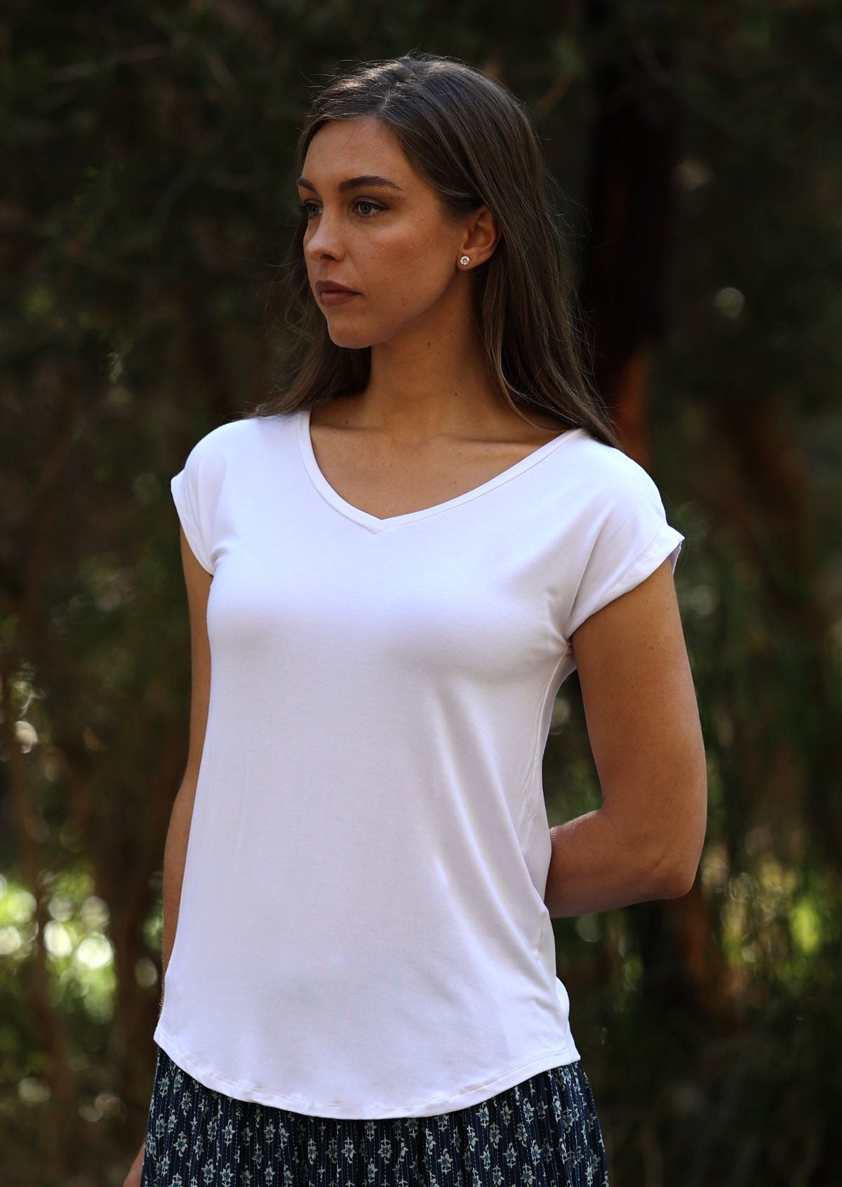 Woman wearing a white v-neck short cap sleeve rayon top.