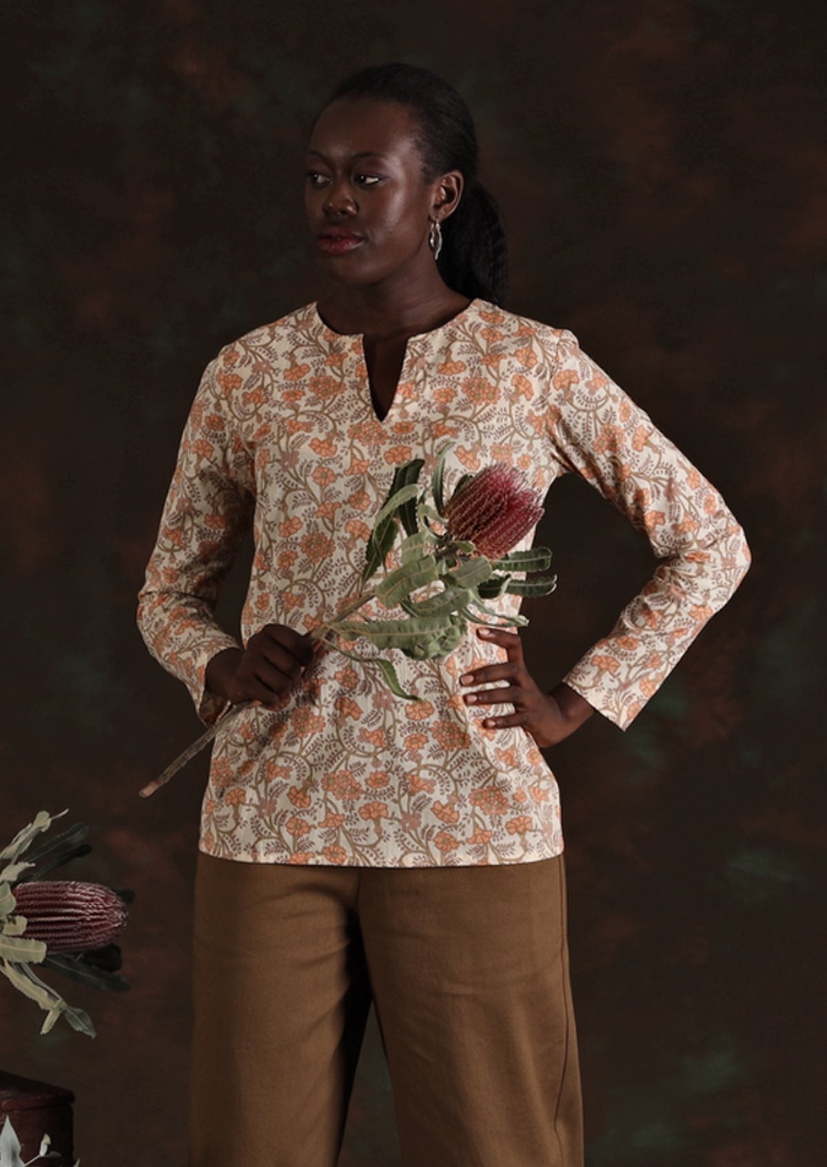 Model in cream floral Sophia Blouse in Liberty print holding large flower