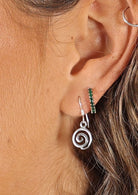 woman's ear with silver spiral earrings