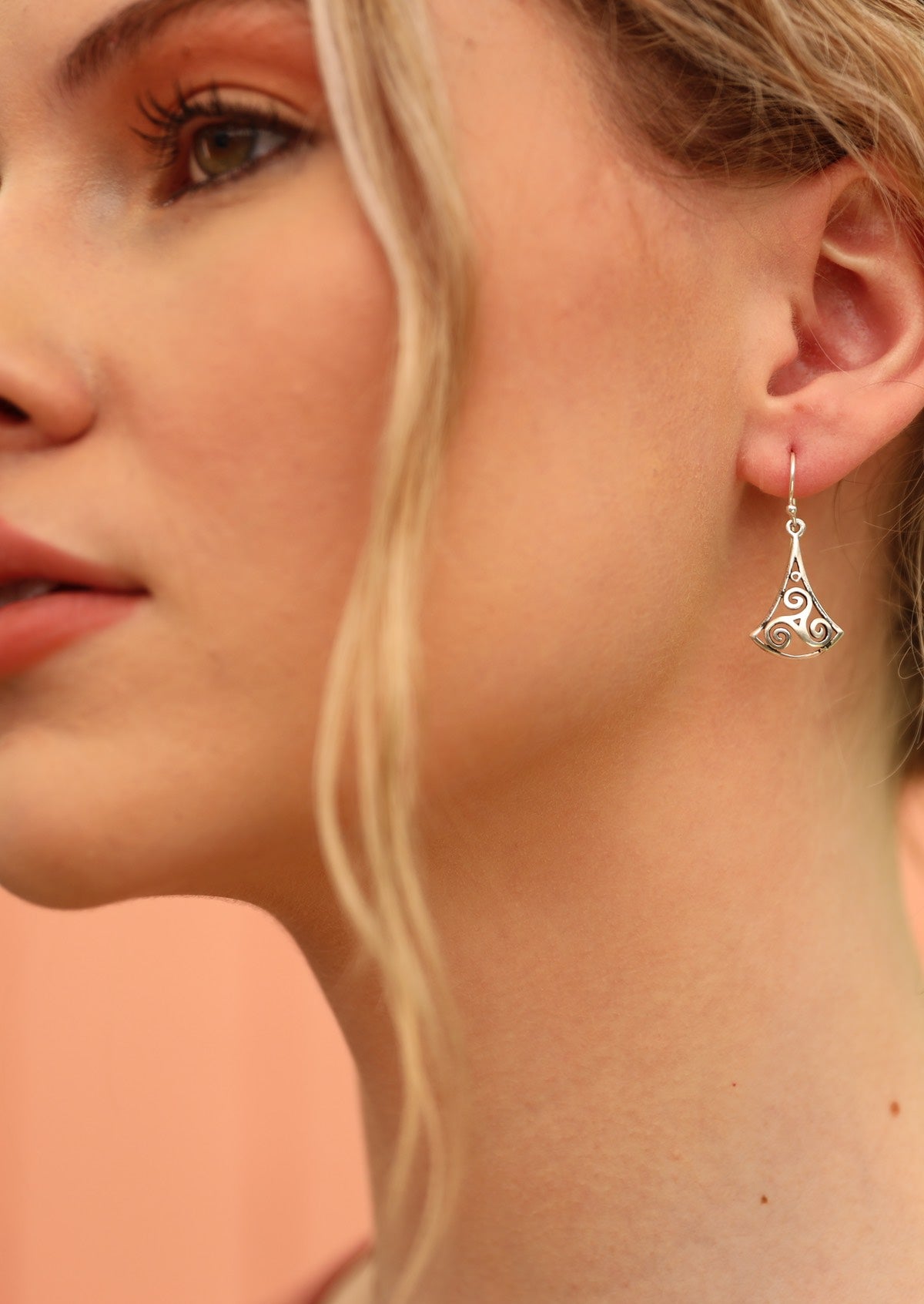 Model wears sterling silver swirly triangle hook earrings