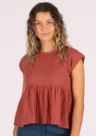 Model wears terracotta coloured cotton gause top with ruffle