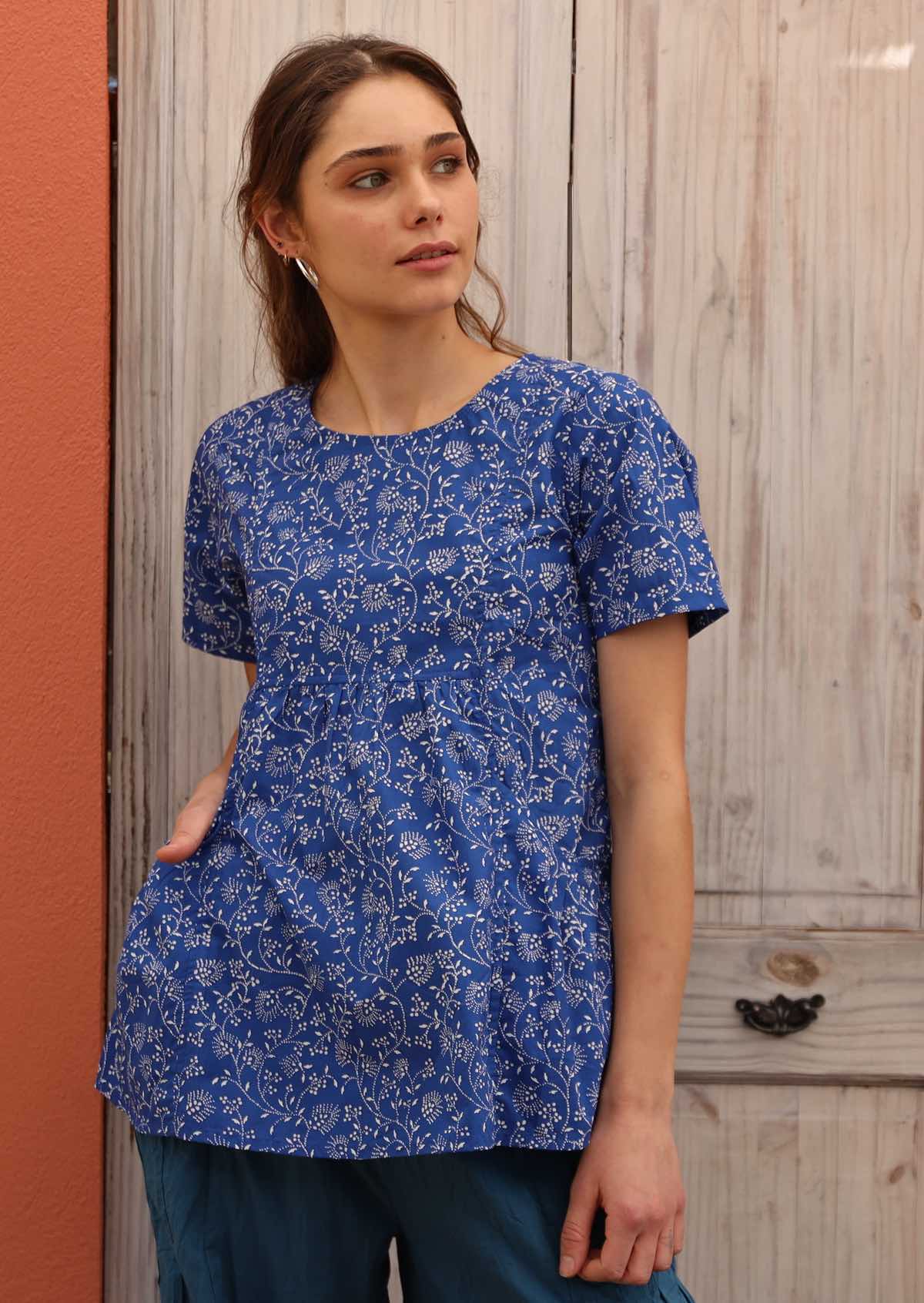 Model pairs blue cotton top that features pockets with blue pants. 