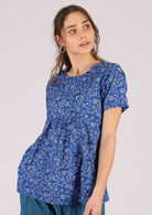 Model wears loose fitting blue top with white florals in 100% cotton. 