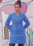 Model wears long sleeve tunic with functional buttons down the chest. 