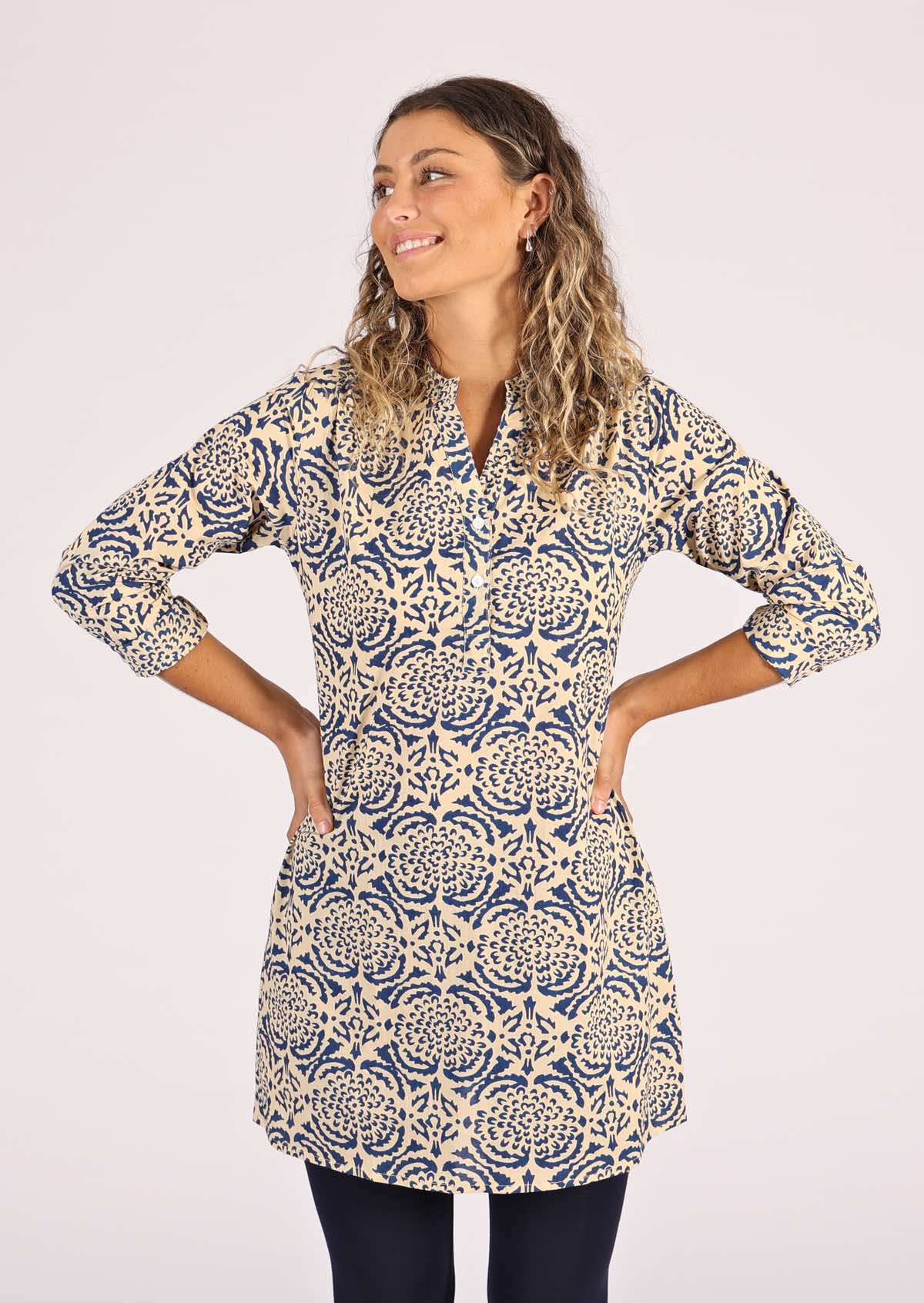 Smiling model wears a long sleeve tunic with functional buttons. 