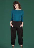 Smiling model wears high waisted black pants with pockets. 