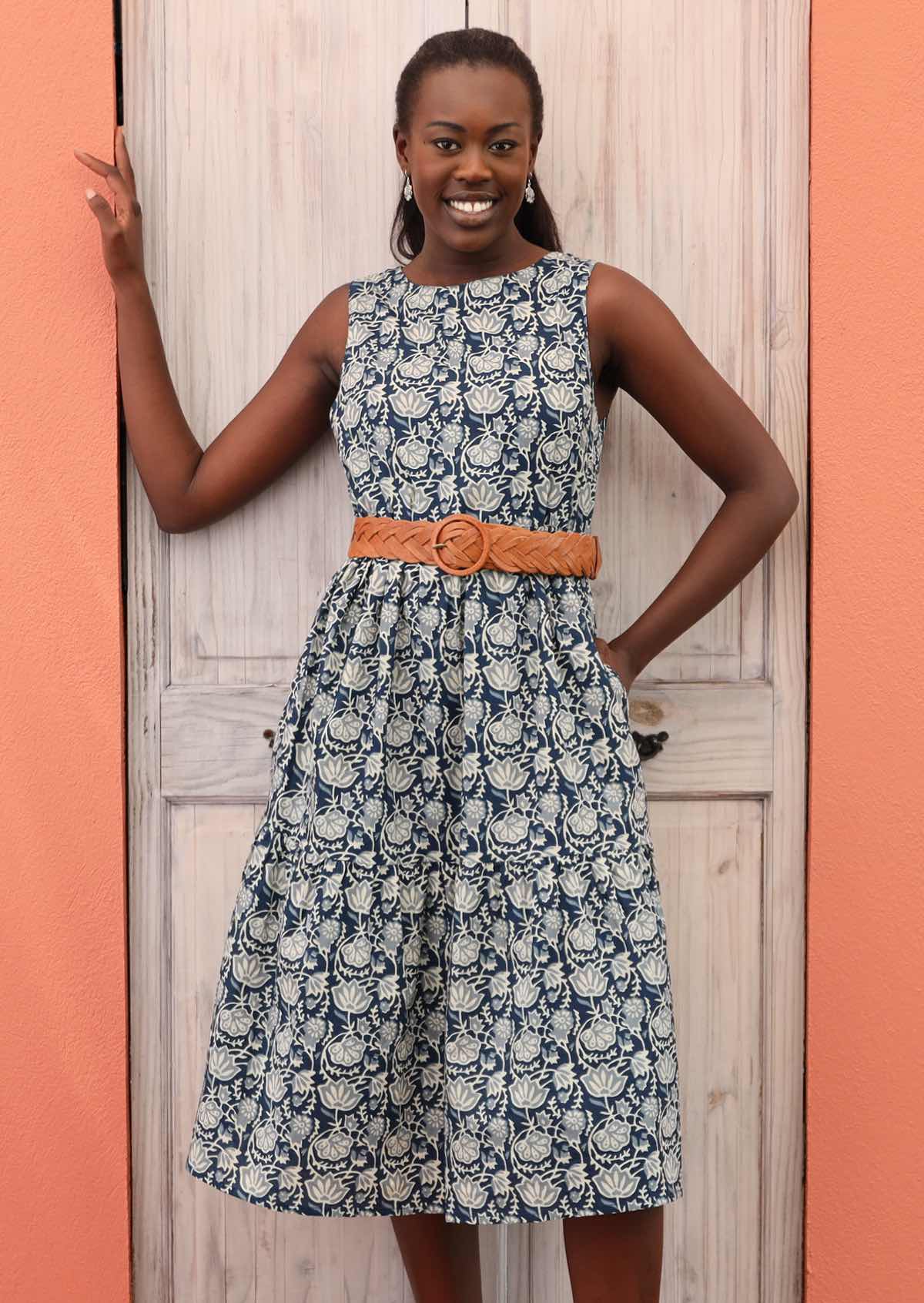 Model pairs blue floral dress with a belt for a cinched waist. 