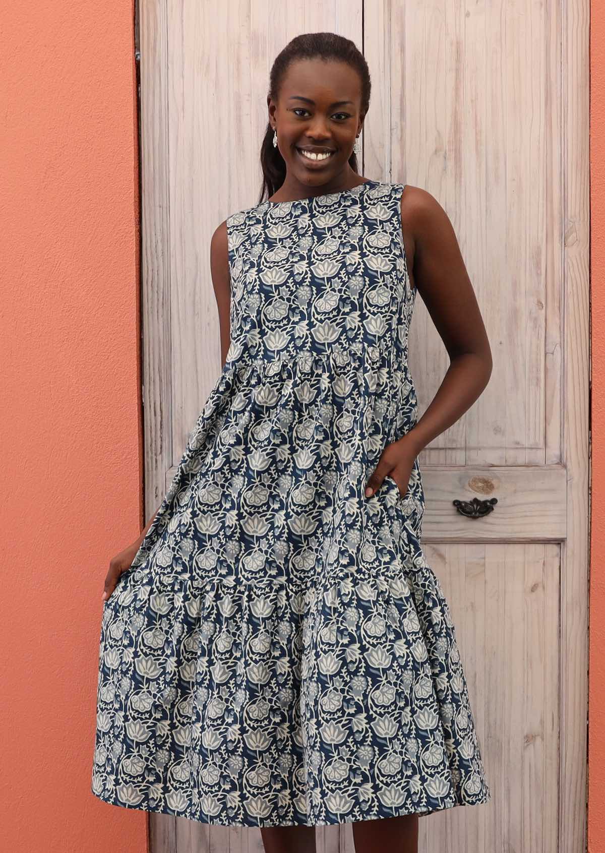 Smiling model holds out the skirt of her three tiered dress. 