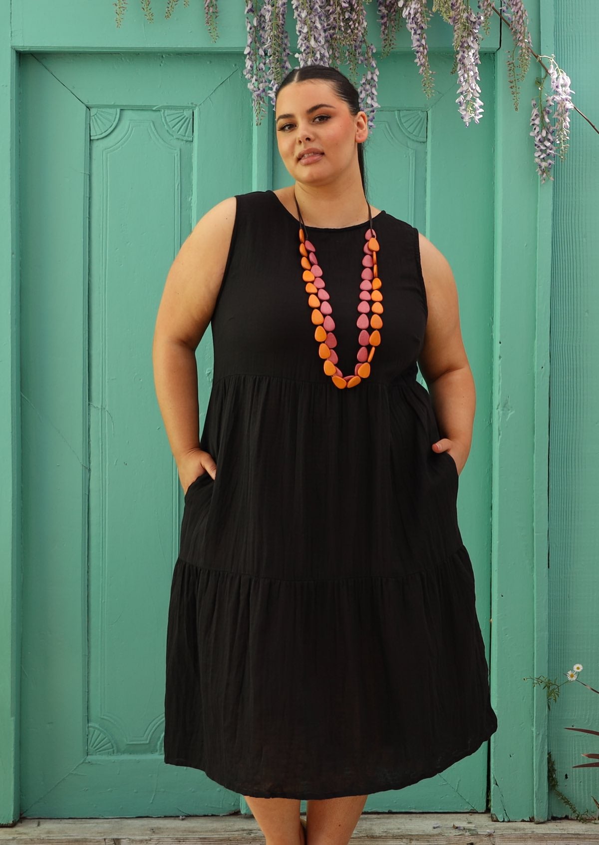 Plus sized woman wearing below knee cotton black dress with bright beads
