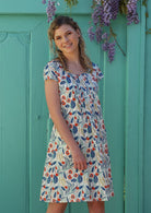 Model wears cotton floral dress with round neckline and cap sleeves 