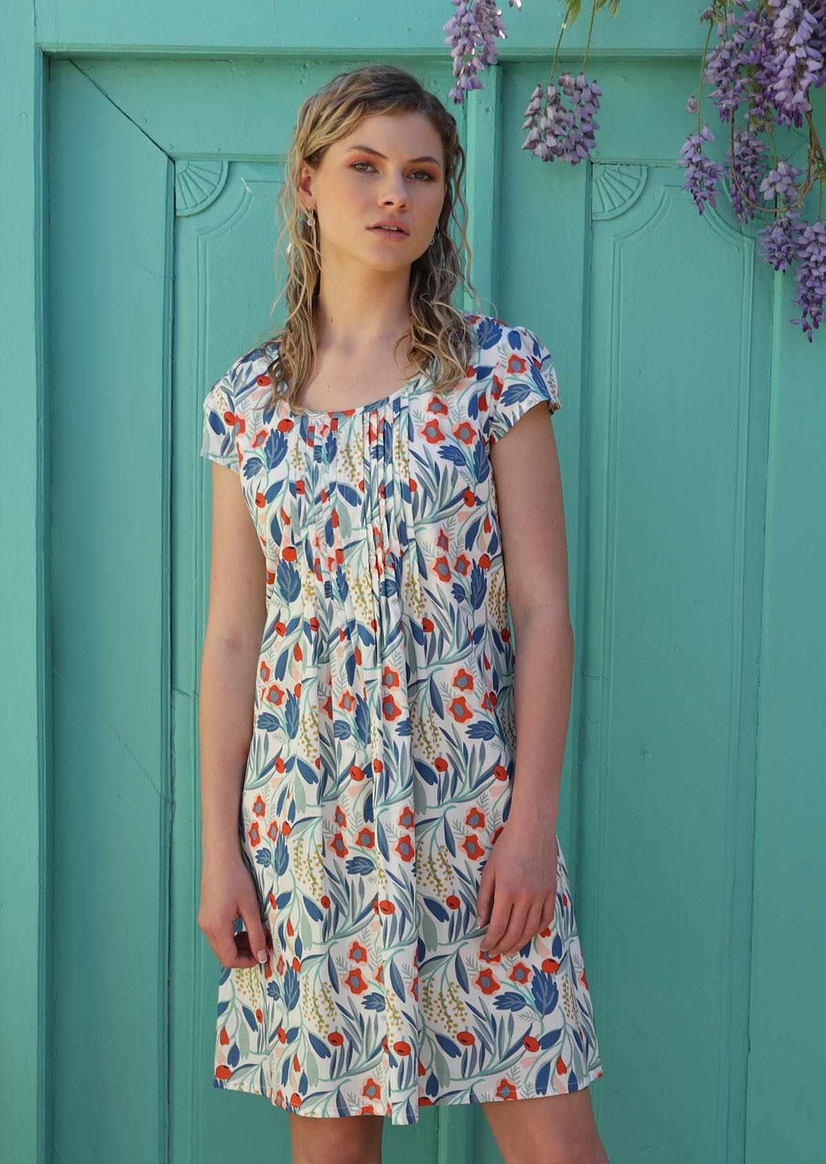Model wears lightweight cotton dress with front pin tucks and cap sleeves