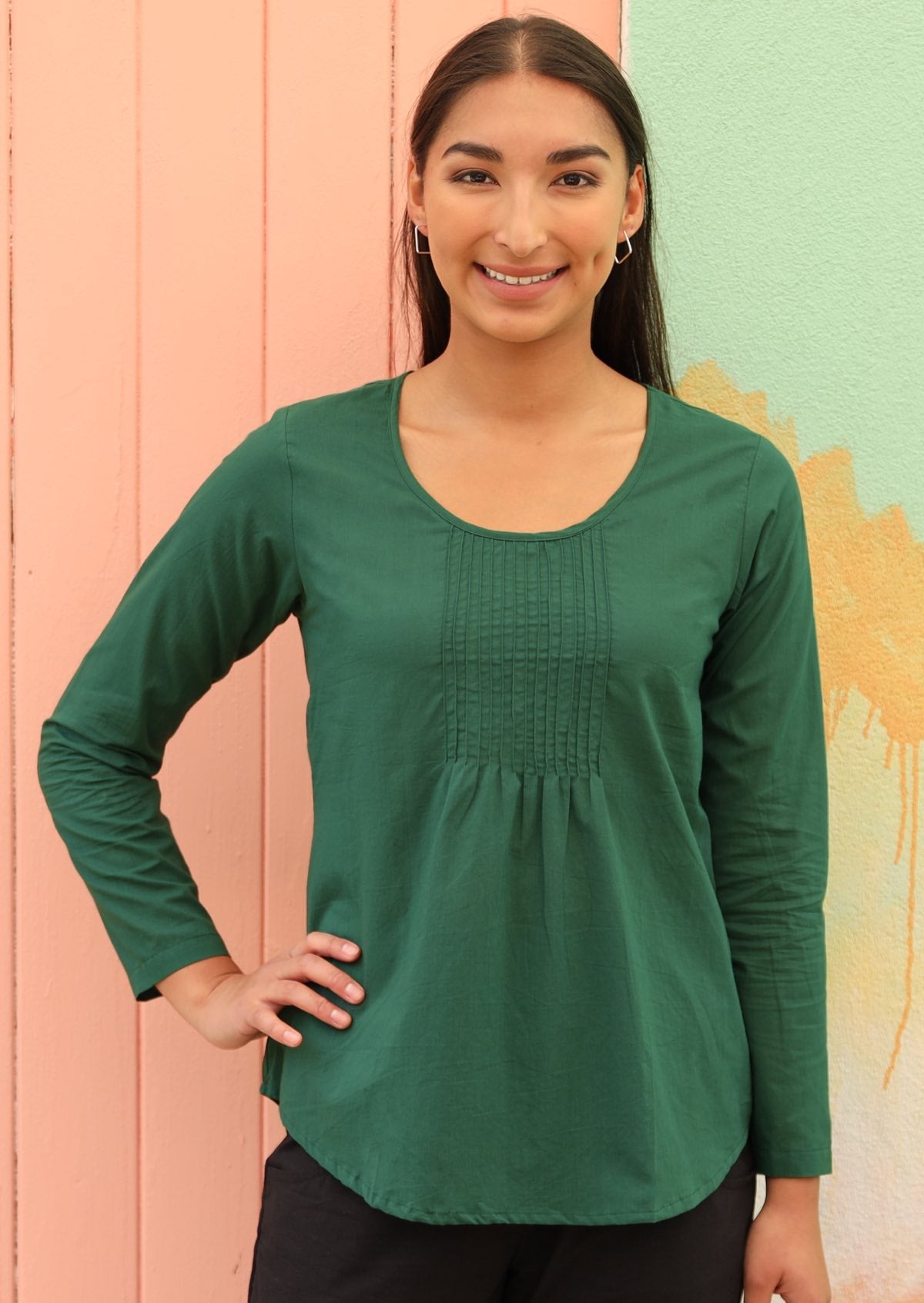 Model smiles in lightweight dark green long sleeve cotton top