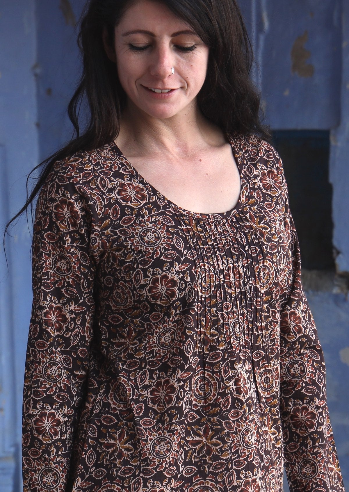 Woman wearing 100% cotton long sleeve top with tiny pleated details and round neck.