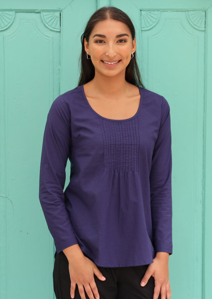 Model is wearing long sleeve dark blue cotton top with pintucks