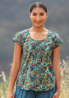Model wears green floral top with cap sleeves. 