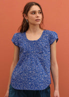 Model wears blue 100% cotton top with cap sleeves. 