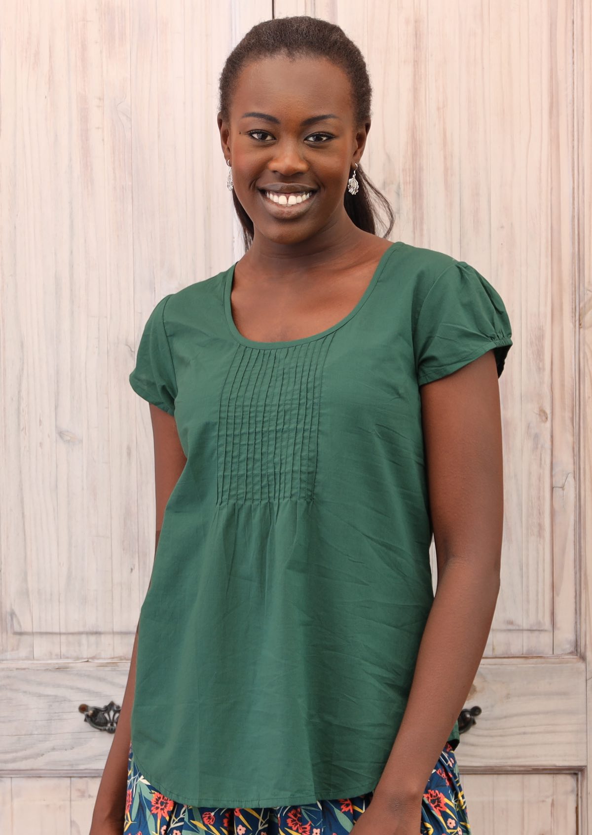 Smiling model pairs green cotton top with a colourful skirt. 