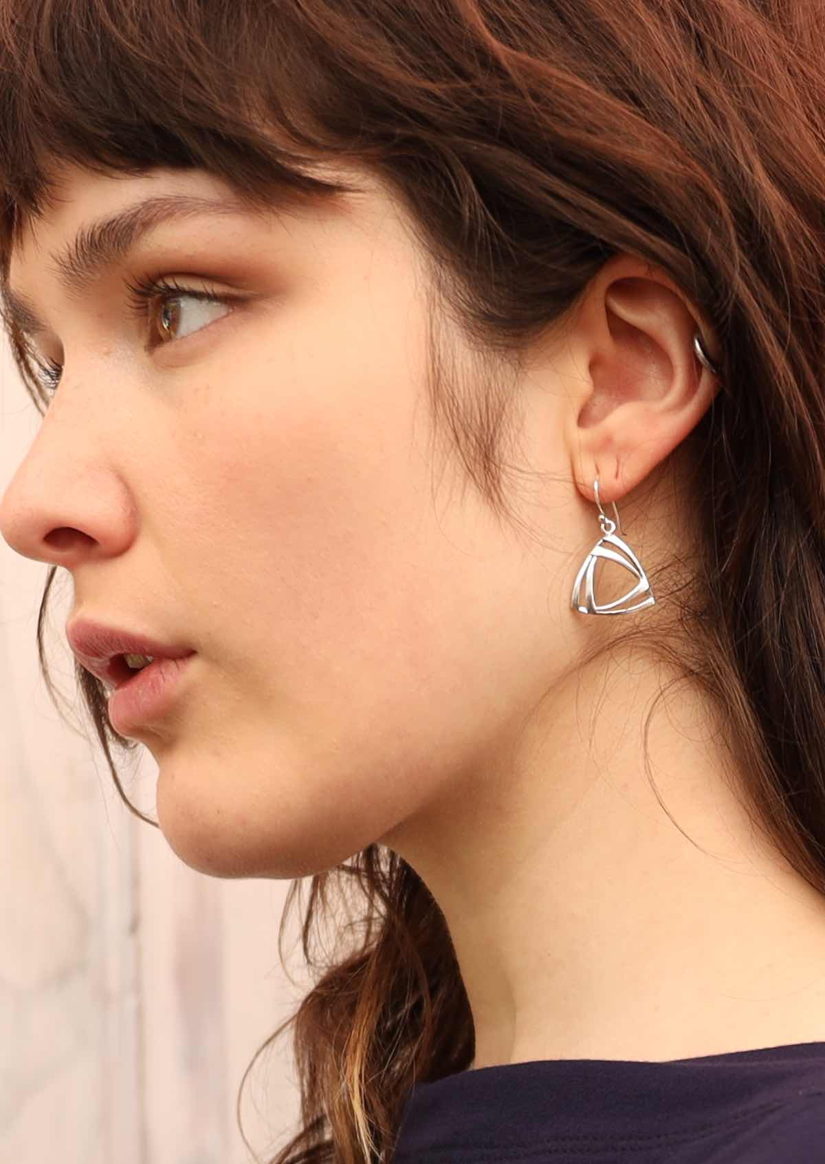 Model wearing dangly silver triangle earrings