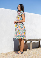 Woman in a pastel cotton buttoned bodice shirt dress with a collar and cap sleeves