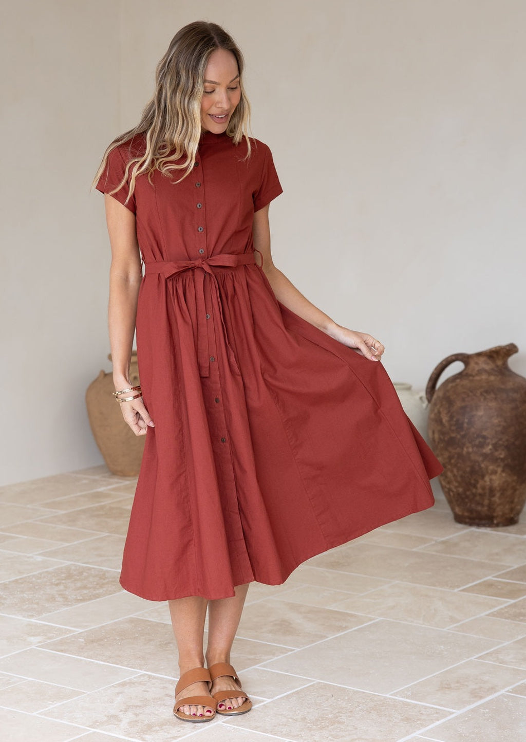 Model flaunts a 100% cotton midi-length dress with pockets, a mandarin collar, detachable waist tie, and small pleats at the center waist