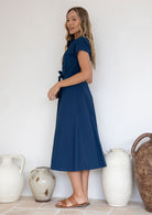 Woman wears 100% cotton midi length dress with short sleeves, waist tie and pockets