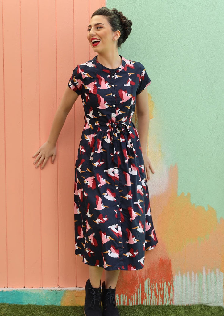 Model with dark hair wearing navy blue retro style dress with pelican print 