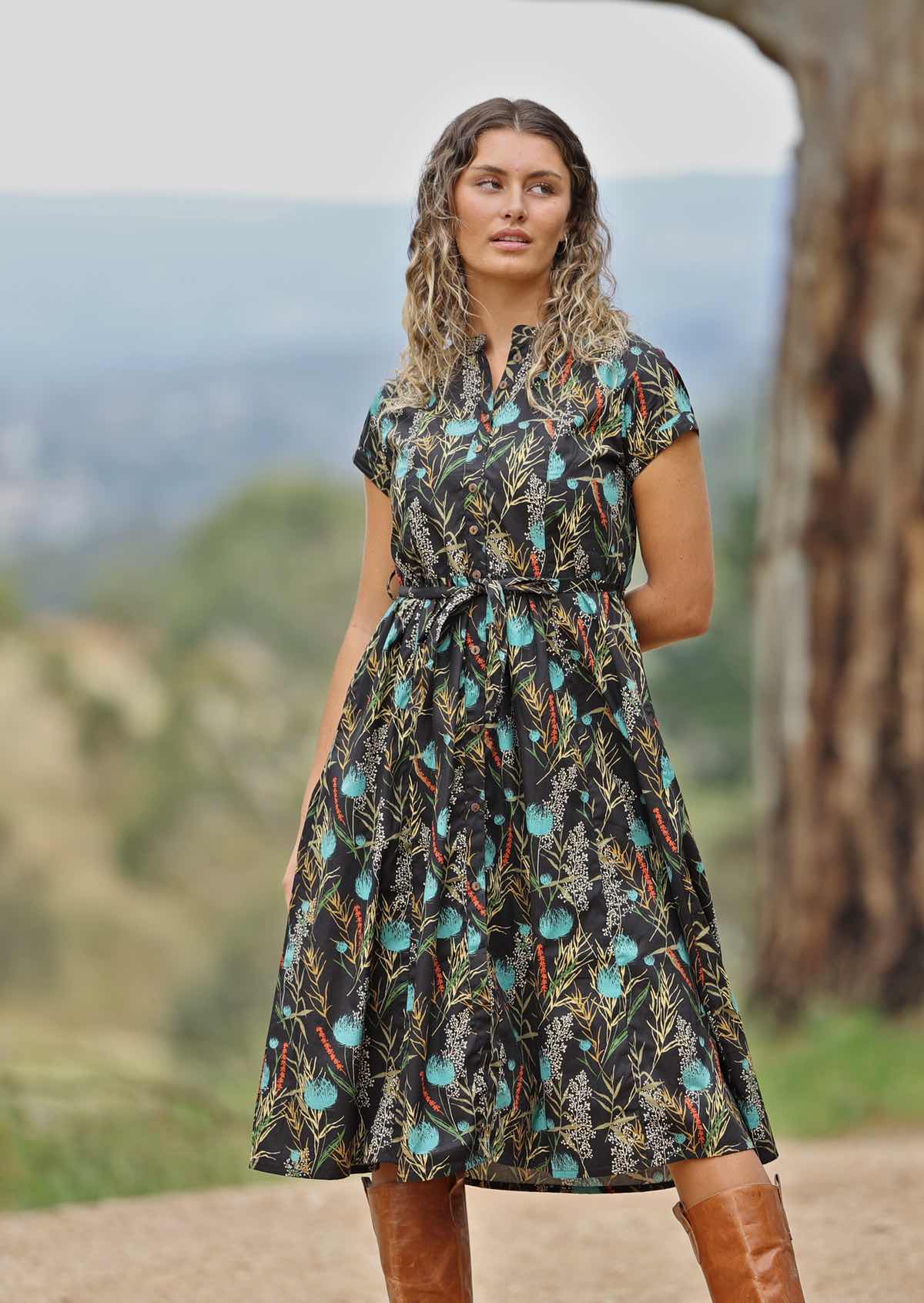 woman on hill wearing black cotton retro dress with teal floral print