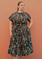 Plus size model wearing Vivien dress in black and teal with pockets and buttons