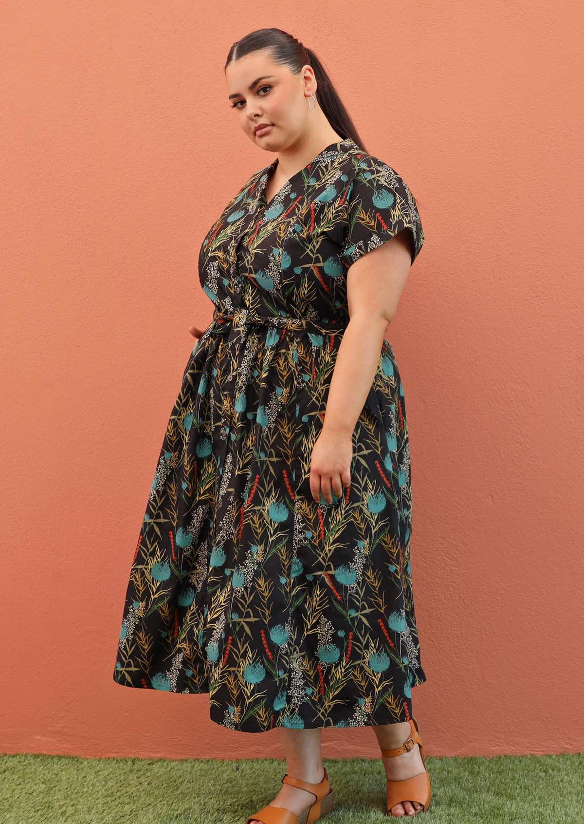 Plus size model wearing Vivien dress in black and teal with pockets