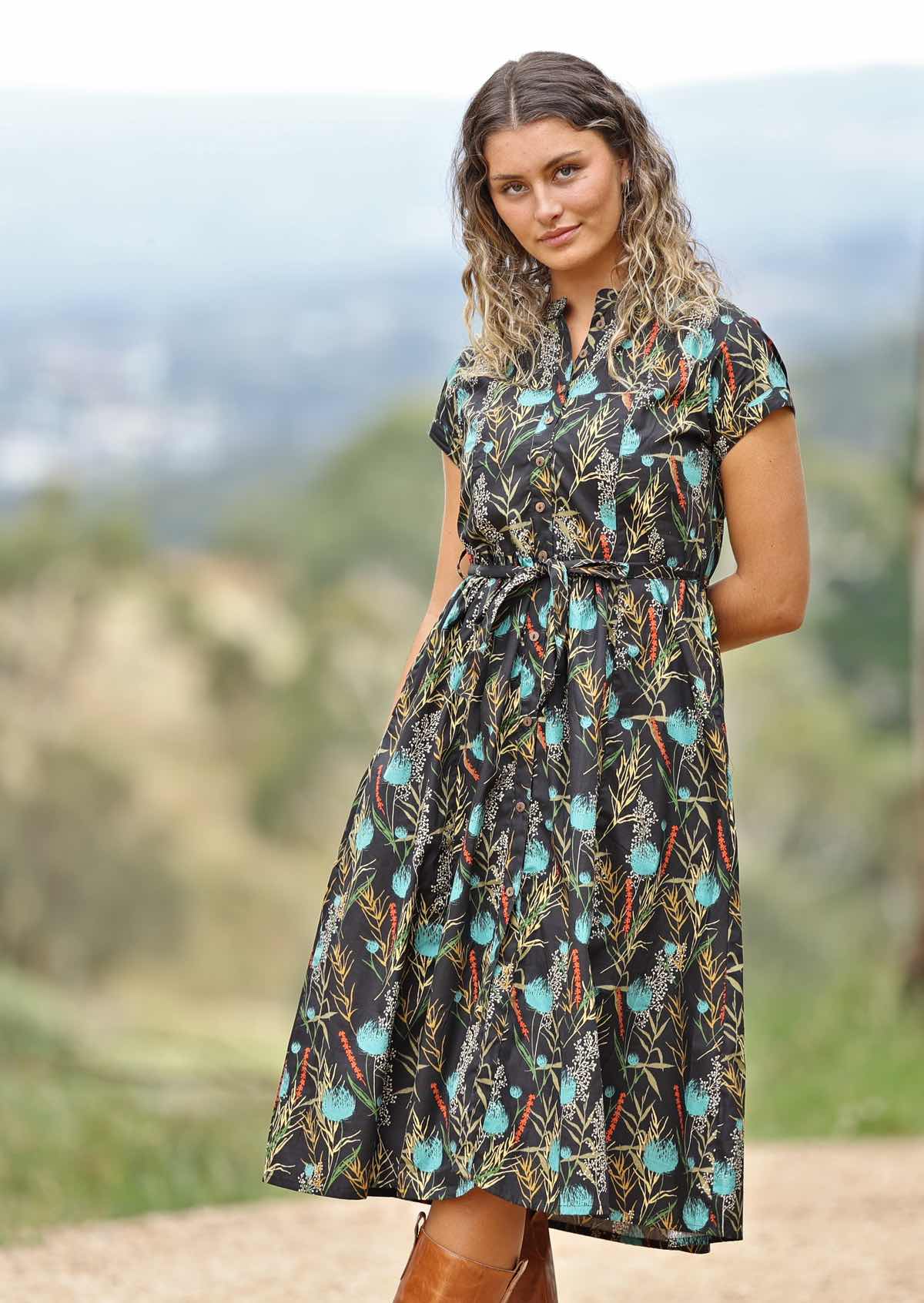 Model on hill wearing black cotton retro dress with teal native floral print