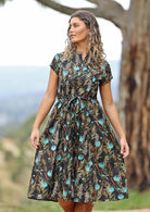 Model on hill wearing black cotton maxi dress with teal floral print