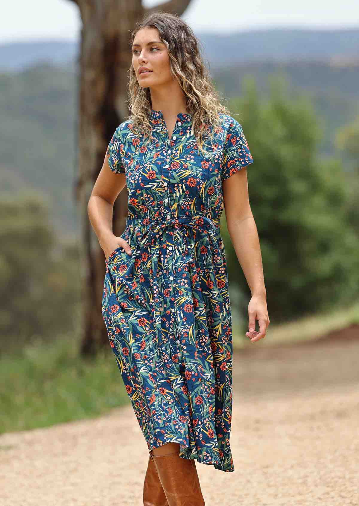 woman wearing floral button up retro style teal blue maxi dress trees and hills in background